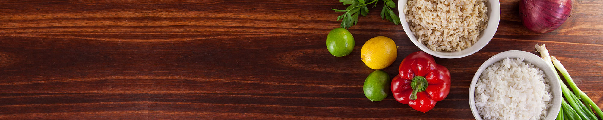 Overhead view of cooked rice and vegetables on wooden table.