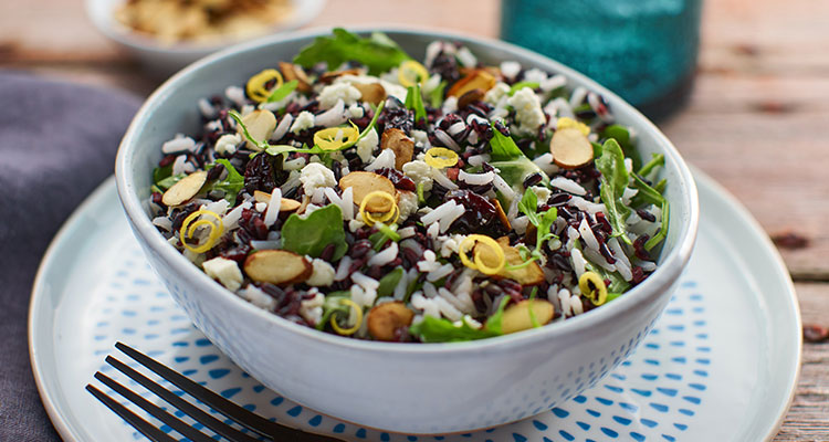 Side view of arugula and rice salad in a blue bowl.