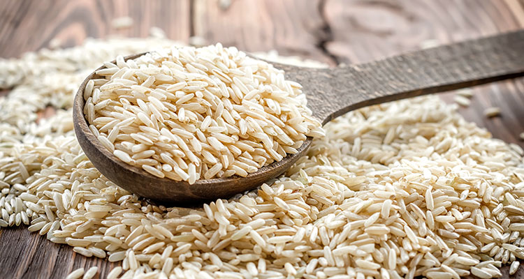 Side view of brown rice grains on a wooden table.