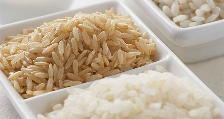 Overhead view of different types of rice in wooden bowls.