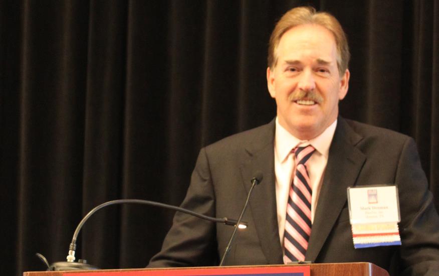 White man stands behind podium with poster for Outlook Conference St Louis MO 2013