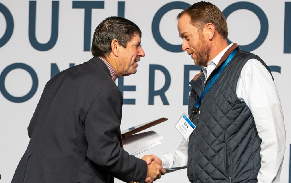 Two men talk and shake hands during award presentation