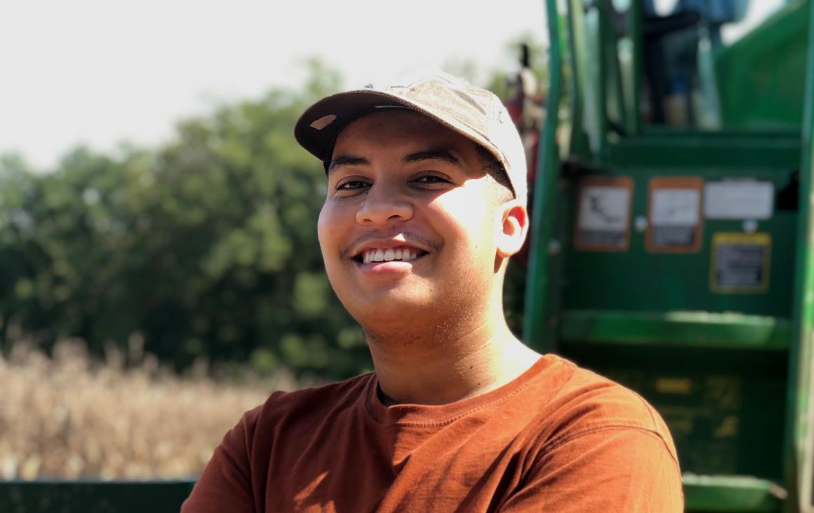 Philip Haynie IV wearing ballcap, with tractor in background