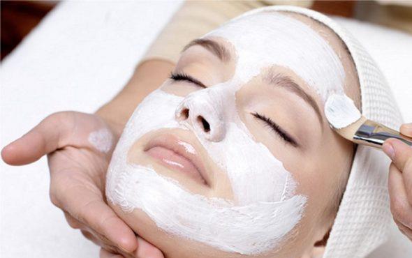 Rice Face Mask Application on female face, makeup brush coating white substance on woman whose eyes are closed