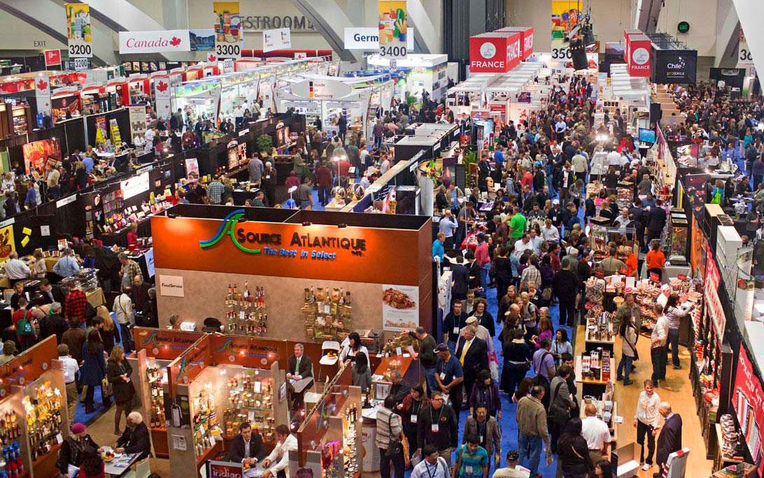 Overhead view of 2023 Fancy Food trade show floor shows crowds of people milling around demonstration booths