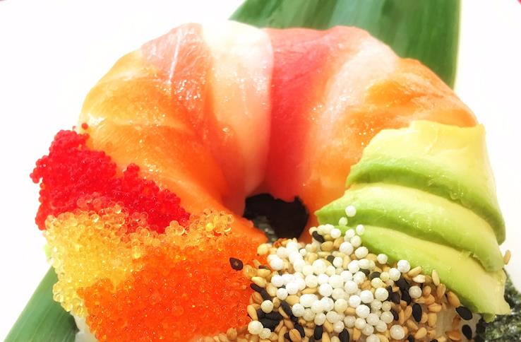 Sushi Zen Donut with green avocado slices, red & yellow fish roe, sesame seeds on a bed of nori