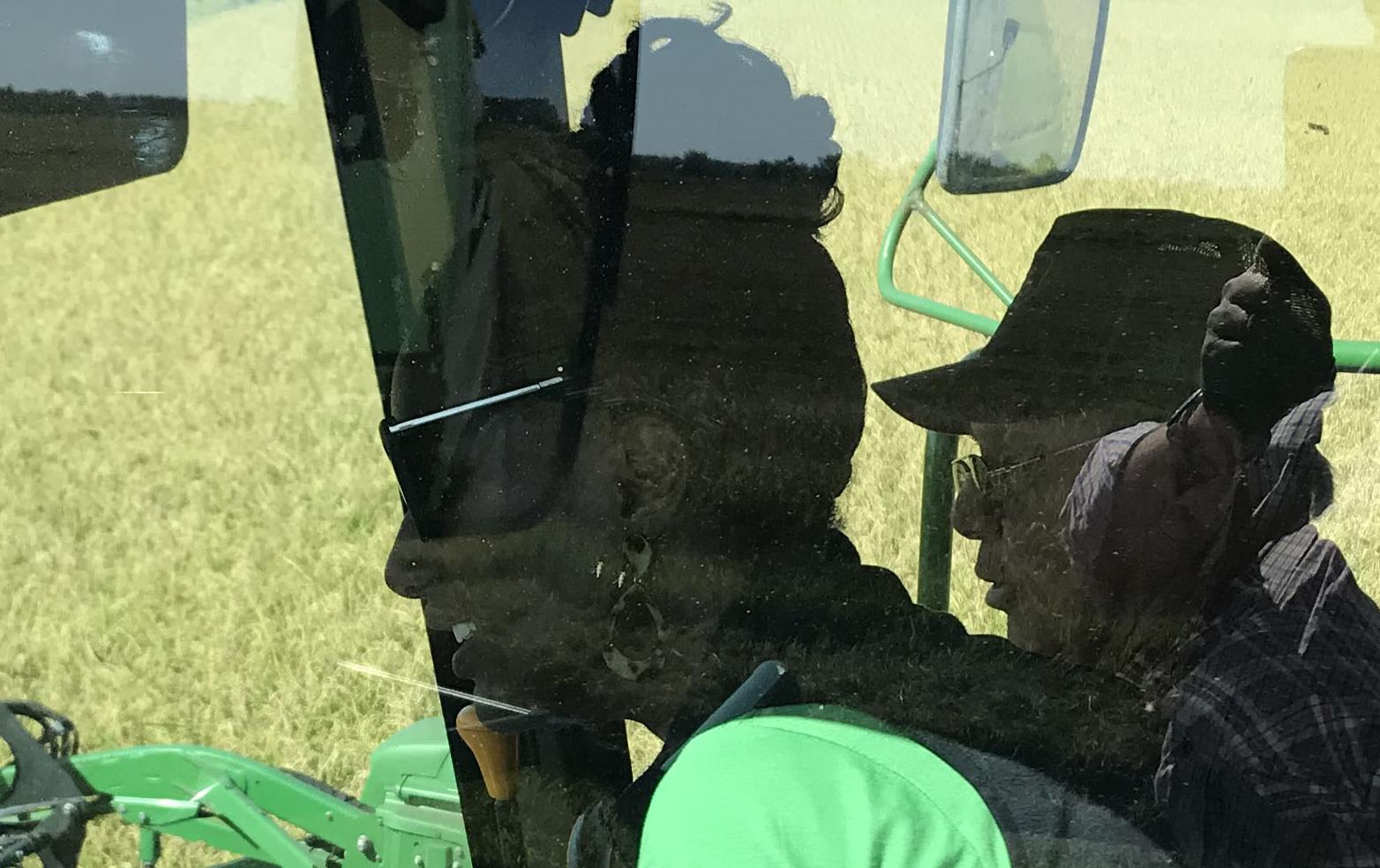  Two people in cab of combine cutting rice