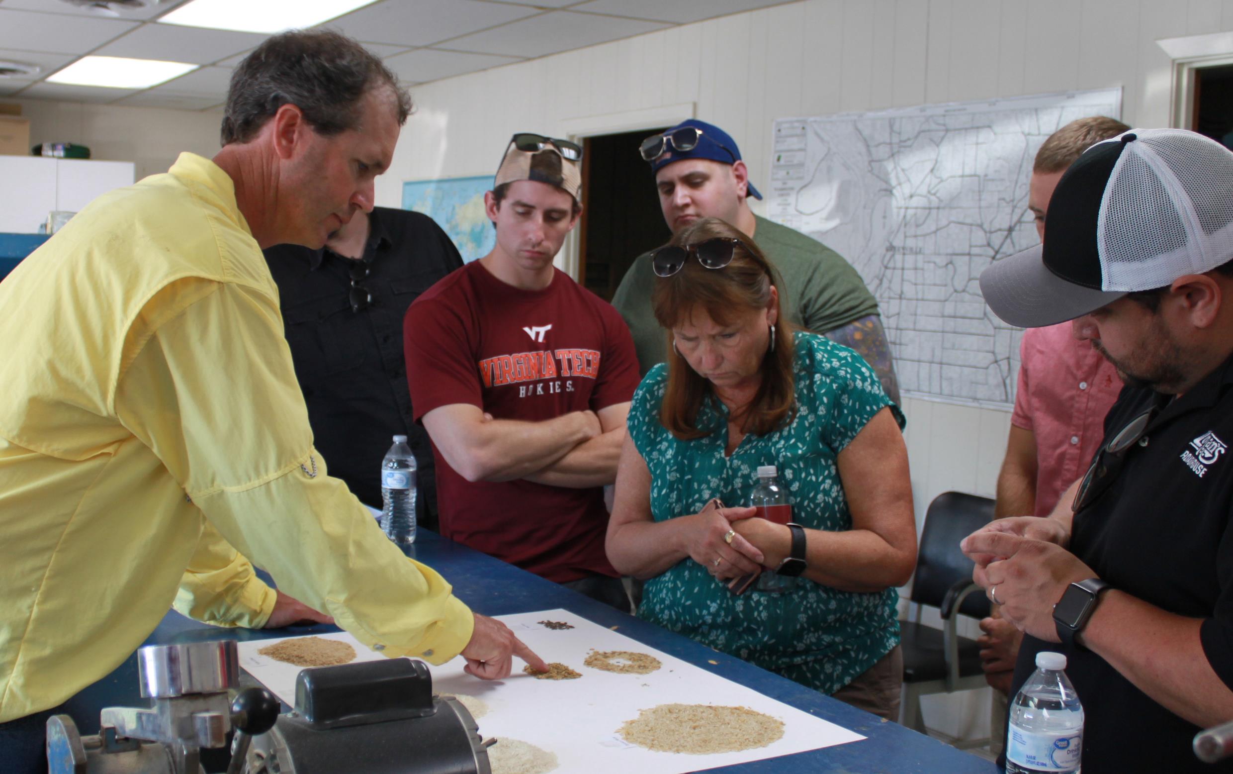 People gathered around blue-topped table for milling demo