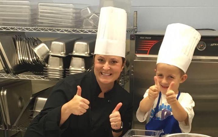 Woman and young boy wearing toques give the thumbs up sign