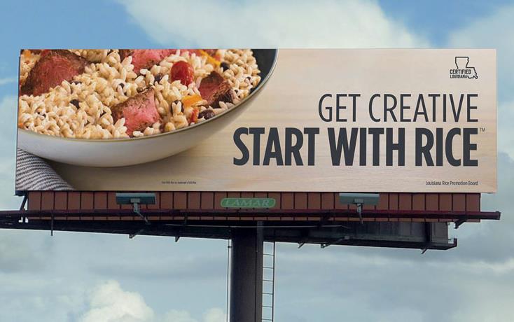 Billboard with bowl of rice and meat w/text "Get Creative Start With Rice" against blue sky & white clouds