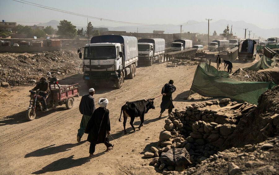 Truck convoy-on the road in-Kabul, Afghanistan, other vehicles, including motorcycle carts, and people walking with livestock crowd the street