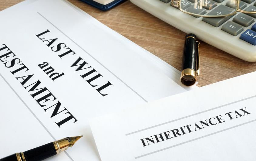 Papers on desk in front on computer keyboard read "Last Will & Testament" and "Inheritance-Tax"