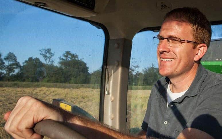 Smiling farmer in combine cab with hands on the steering wheel