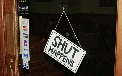 Sign on glass door of business saying "Shut Happens"