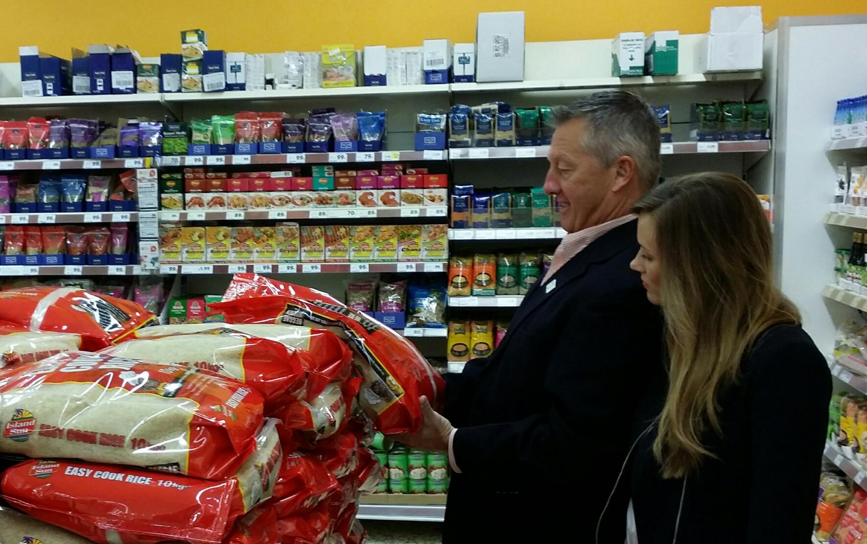 Man and woman in grocery store look at large bags of rice stacked in the aisle