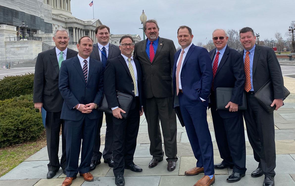 Group of business men stand on sidewalk outside US Capitol