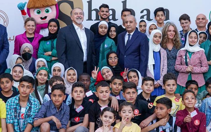 Group of adults and children in front of giant poster