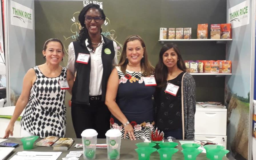 A.-Grigsby-&-crew-in USA Rice booth at-2019-Trade-Show standing behind table filled with swag