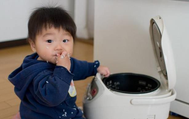 Young boy eating from rice cooker, rice all over the floor, Yoshiyasu Nishikawa photo