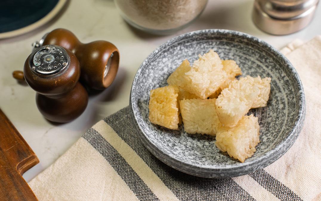 Rice croutons in bowl next to salt & pepper shakers