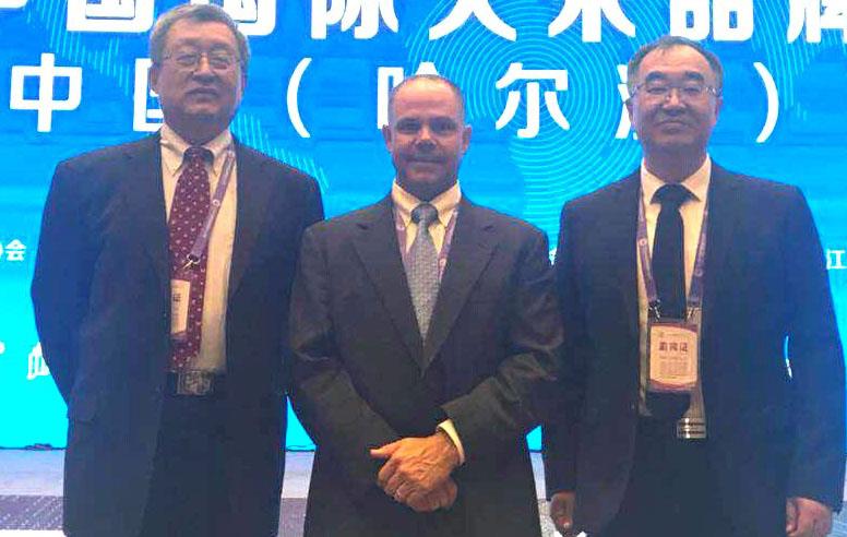 China Rice Festival, 3 men wearing suits stand in front of bright blue banner w/Chinese character writing