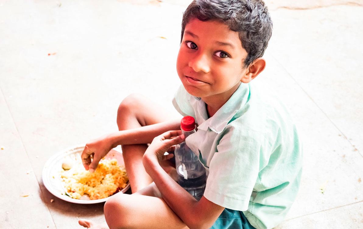 Young-boy-sitting-on-ground-eating-rice