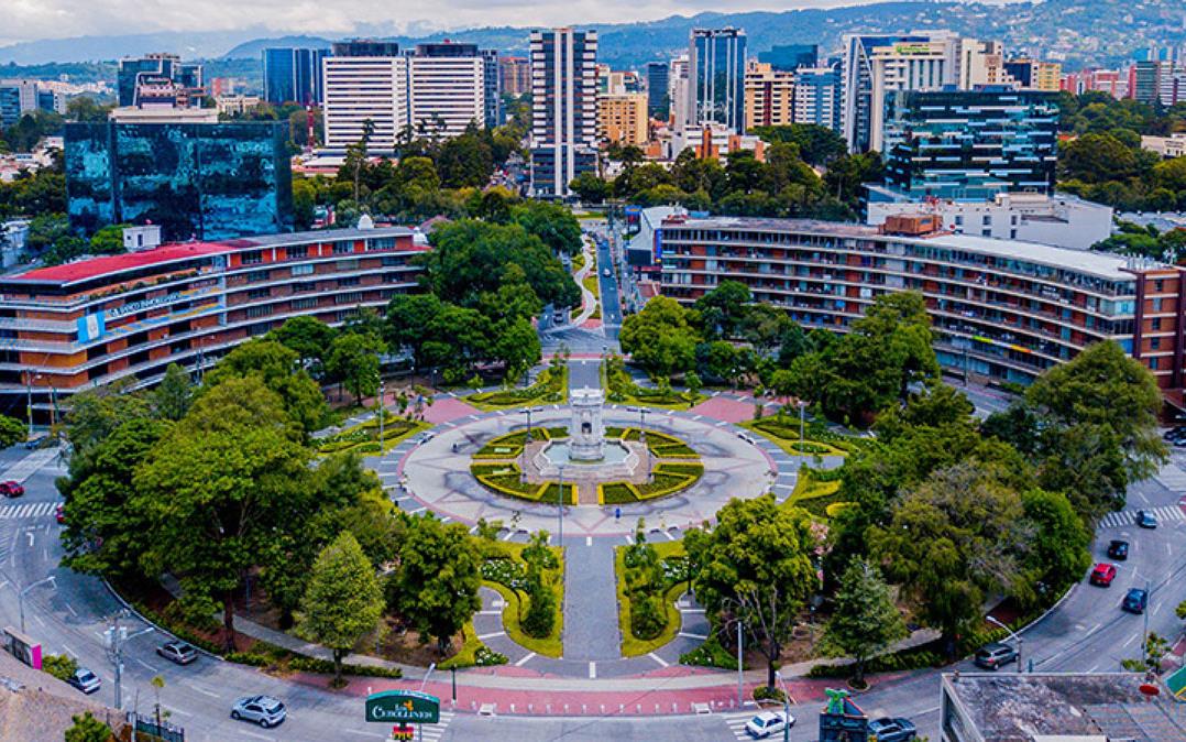 Guatemala-downtown-scene, traffic circle surrounding park space with trees and central statue