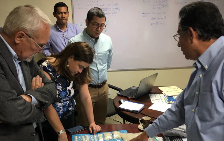 People gathered around a table examine rice samples in clear plastic bags