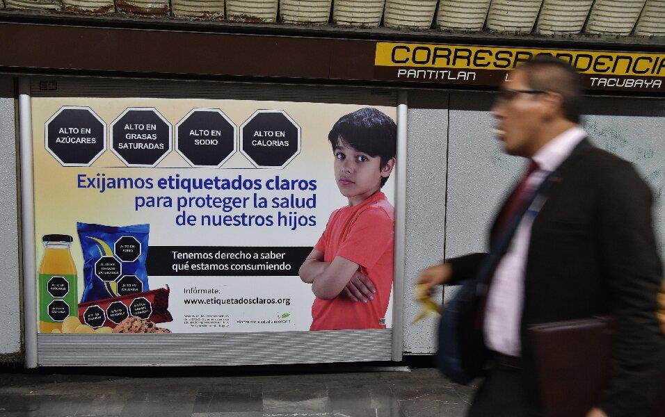 Poster in subway station shows young boy with junk food and warning labels in Spanish