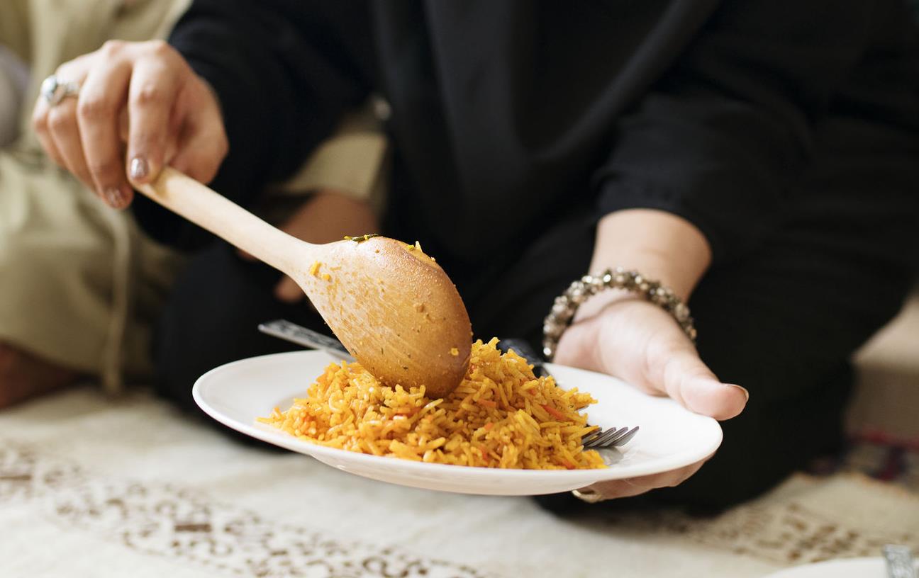 Woman offers plate filled with rice as man and young child look on