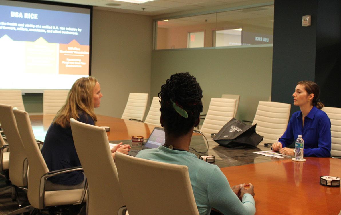 Three women sit at conference room table, talking