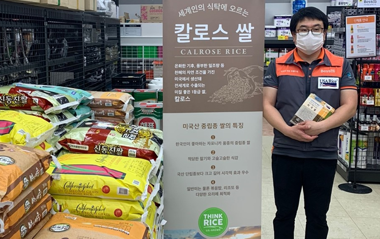 South Korea promo with store employee standing next to sign and stacks of rice bags