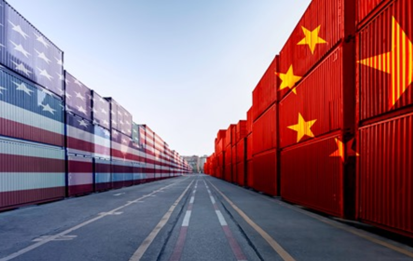 Shipping containers on a loading dock, stack on left side painted with US flag, stack on right side painted with Chinese flag