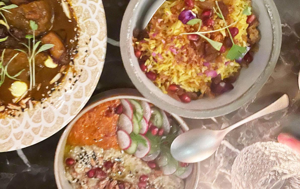 Bowls of colorful rice dishes with cutlery and stemware