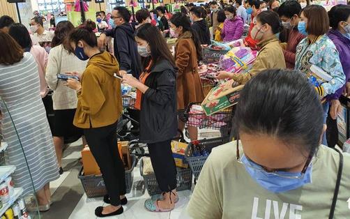 Crowds at grocery store wearing masks, standing in checkout lines, panic buying 