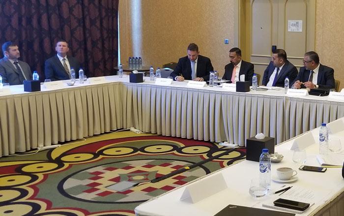 Group of people wearing business attire sit around large conference room table