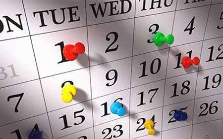 Monthly calendar with colorful thumbtacks stuck in different dates