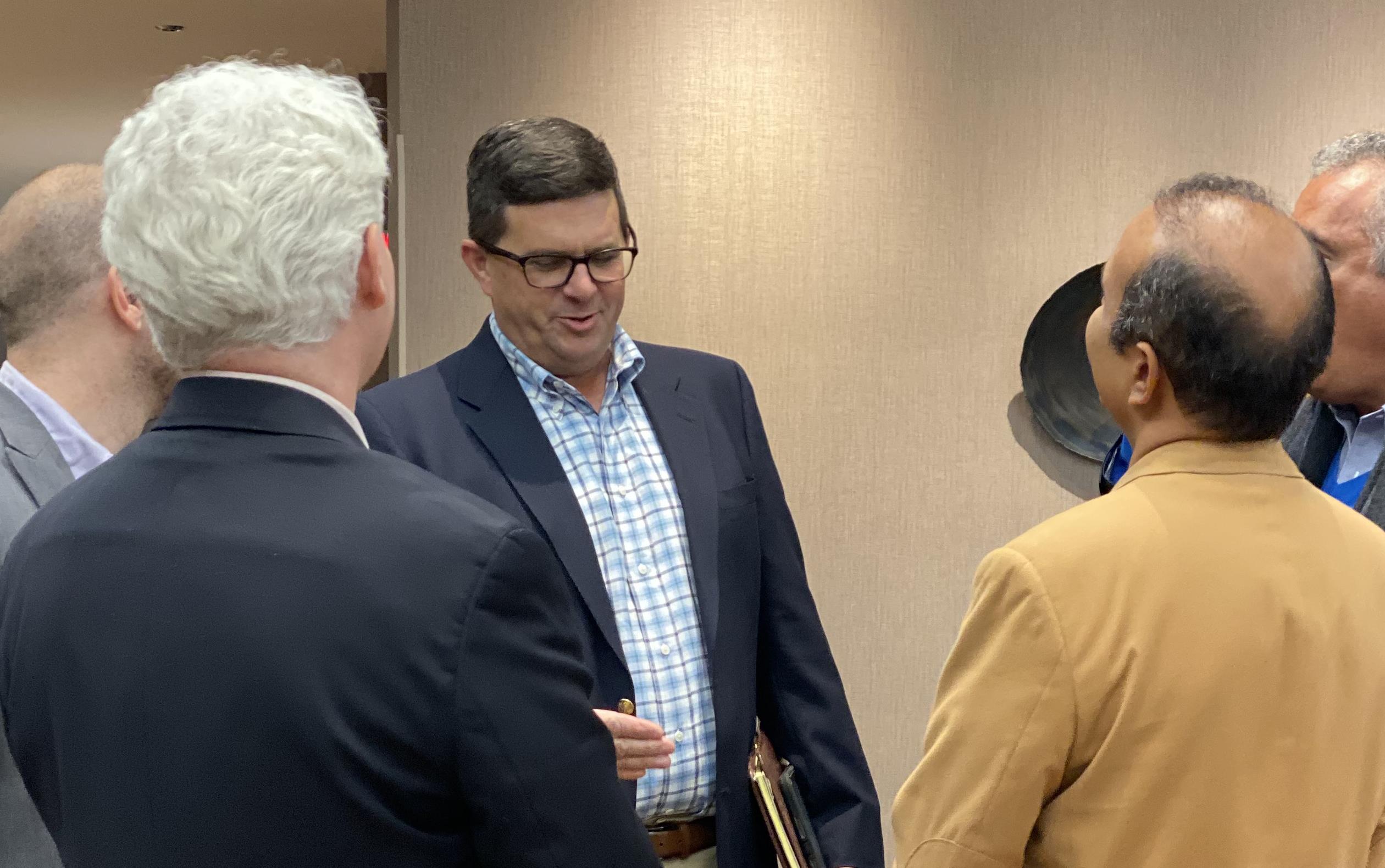 Men in business attire stand in a group talking