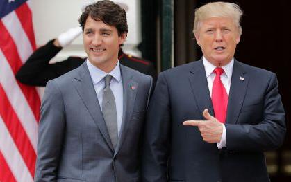  Justin Trudeau President Trump wearing dark suits, standing in front of US flag, Trump points to Trudeau