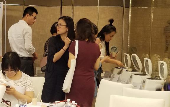 Group of Chinese people line up to taste test rice from four rice cookers on a table