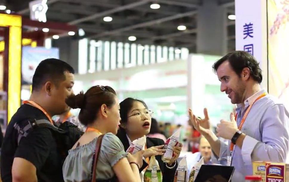 People gather around a booth at a trade seminar holding rice products