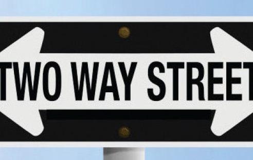 Street sign with arrows pointing in opposite directions says "Two Way Street"