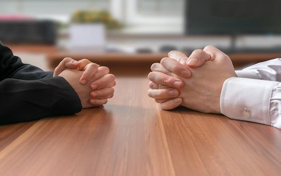 Two sets of clasped hands on wooden table