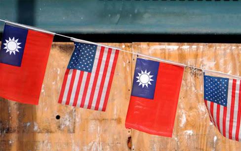 US and Taiwan flags fly on string in front of wooden board