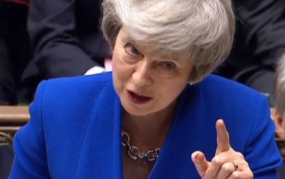  British PM Theresa May wearing royal blue suit & silver necklace, pointing index finger at crowd