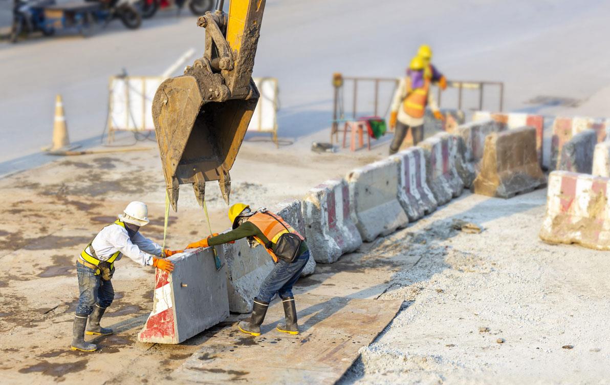 Construction crew setting up concrete traffic barriers 