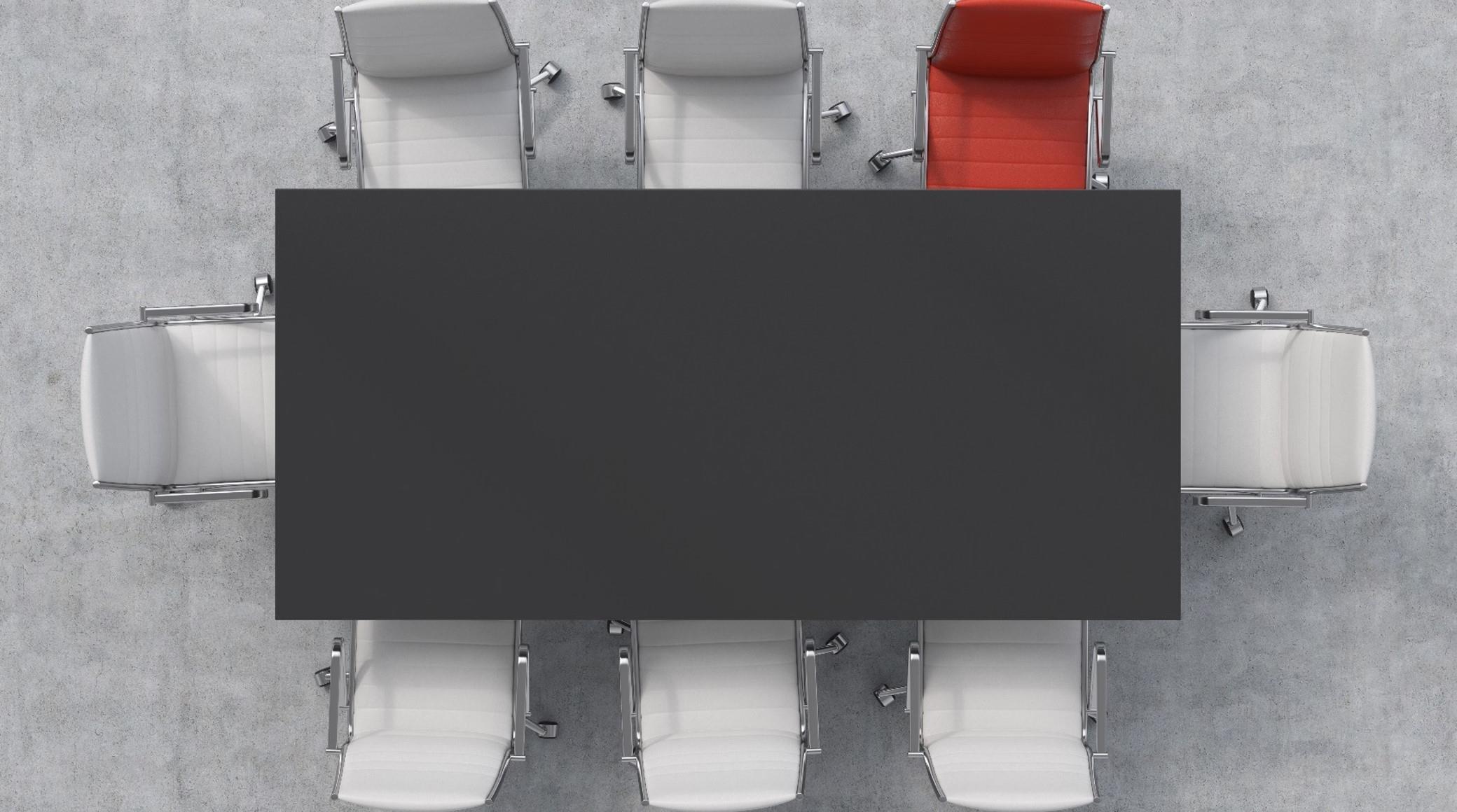 Aerial view of rectangular black table surrounded by white chairs plus one red chair