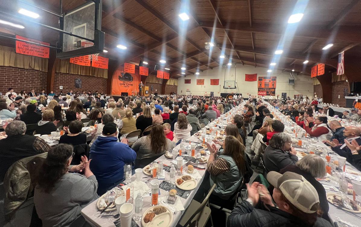 AR-Coon-Supper, diners seated at food-laden tables inside gymnasium