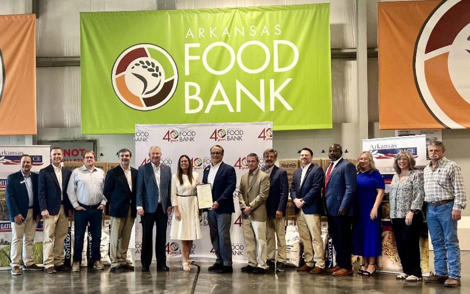 AR-Rice-Donation-group-shot of people standing in front of large, colorful AR Food Bank banners 