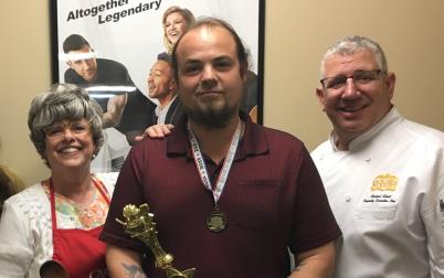 Group shot of Cajun Country Recipe Contest winner holding trophy flanked by both a male and female chef, along with the Intl Rice Queen wearing her tiara and another man wearing a business suit